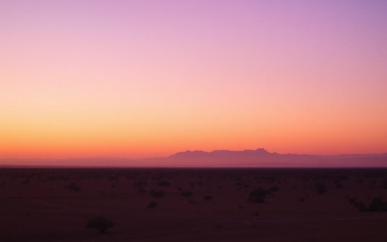 Wide outback landscape at dusk with warm orange and purple sky